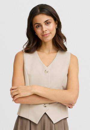 Gilet beige sans manches avec un col en V, deux boutons et une coupe ajustée, fabriqué en tissu lisse avec une forme légèrement structurée.