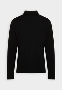 Polo noir à manches longues montré de dos avec un col rabattable et une silhouette ajustée sur un fond clair uni.