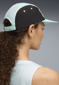 Világoskék és fekete színű baseball sapka, amely szövetből készült, ívelt karimával és állítható pánttal rendelkezik. Ventilációs nyílásokkal van ellátva.