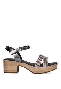 Sandalia con tacón cuadrado que presenta tiras metálicas plateadas y plataforma de madera. Correa ajustable en el tobillo con detalle de hebilla. Tacón texturizado para mayor agarre.
