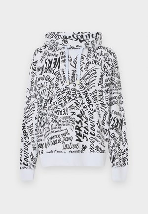 Hettegenser i hvit med et svart håndskrevet stilmønster som inneholder tekst og logoer. Løs passform med ribbestrikkede mansjetter og midje.