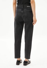 Jean gris foncé taille haute avec une coupe droite, doté de deux poches arrière et d'un patch de marque sur la ceinture. Texture lisse, matériau en denim.