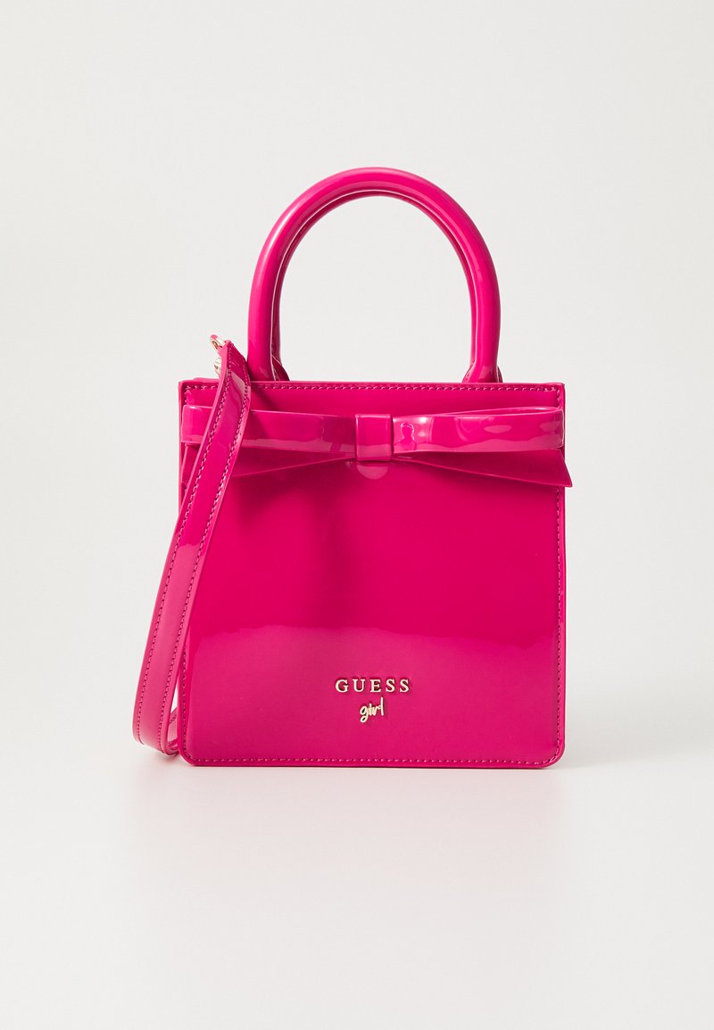 Hot pink patent leather handbag with a bow detail, dual handles, detachable shoulder strap, and embossed "GUESS girl" logo.