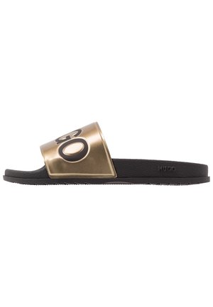Sandale slide noire avec semelle texturée et bride métallique dorée avec grand logo noir "HUGO".