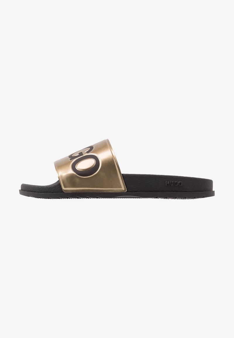 Sandale slide noire avec semelle texturée et bride métallique dorée avec grand logo noir "HUGO".