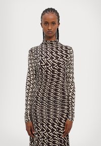 Robe à manches longues avec un motif zigzag marron et crème, présentant un col haut et une silhouette ajustée, fabriquée dans un tissu extensible.