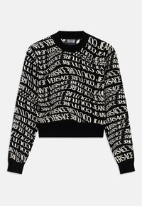 Melna īsa džemperis ar baltiem, viļņojošiem uzrakstiem "VERSACE JEANS COUTURE". Ribota apkakle un piedurknes, adīta tekstūra, minimālistisks dizains.