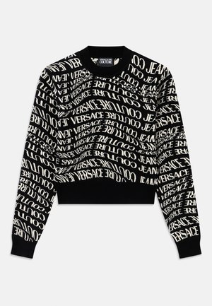 Black cropped sweater with white, swirling text "VERSACE JEANS COUTURE." Ribbed neckline and cuffs, knit texture, minimalistic design.