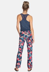 Canottiera senza maniche di colore blu navy con schiena in pizzo, abbinata a pantaloni a stampa floreale nei toni di blu scuro, rosso e verde. Tessuto morbido, vestibilità comoda.