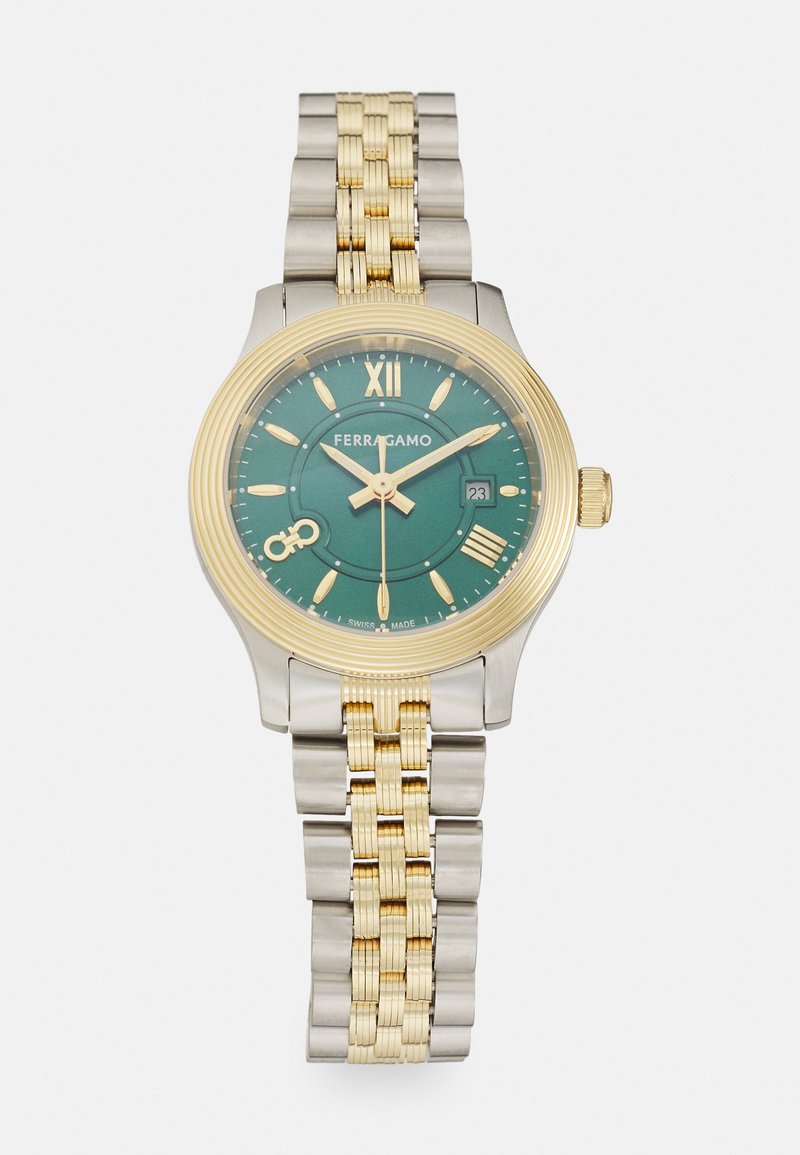 Auksinės ir sidabrinės spalvos nerūdijančio plieno laikrodis su žaliu ciferblatu, valandų žymėjimu ir datos funkcija. Su tekstūruotu rėmeliu ir sujungta apyranke.