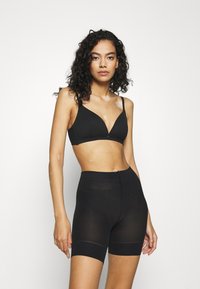 Svart bralette med mjuka kupor och justerbara band, kombinerad med högmidjade svarta shorts i ett stretchtåligt, genomskinligt material.
