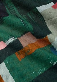 Patrón abstracto de pinceladas de acuarela en tela que presenta formas rectangulares en verde, marrón, negro, blanco, rosa y rojo.
