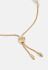 Gold chain bracelet with a round clasp featuring embossed initials. The chain has a textured finish and ends with two polished tips.