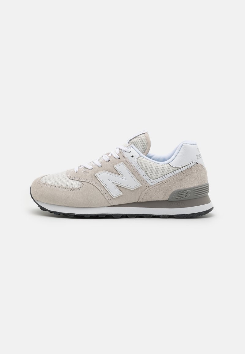 Beige and white New Balance sneaker with suede and mesh upper, white laces, and black rubber sole, shown from lateral side on white background.