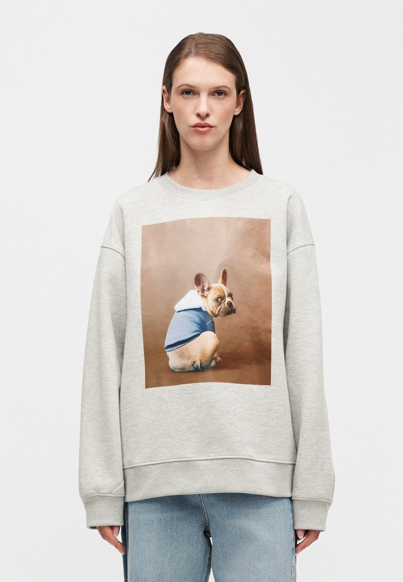 Felpa grigio chiaro con una grande stampa di un bulldog francese che indossa una felpa con cappuccio blu e bianca. Ha una vestibilità comoda e polsini a coste.