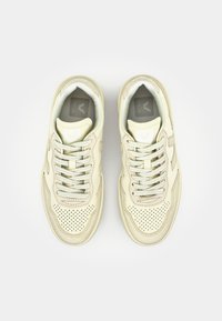 Baskets en cuir beige avec détails perforés, logo blanc contrastant, lacets plats et semelles texturées, vues de dessus.