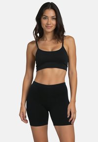 Fekete sportos crop top vékony pántokkal és hozzáillő magas derekú shortokkal, rugalmas anyagból, sima felülettel, testhezálló dizájnnal.