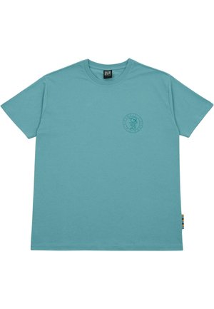 T-shirt en coton bleu clair avec des manches courtes, col rond et un logo graphique circulaire sur la poitrine. La couture latérale présente une étiquette multicolore.