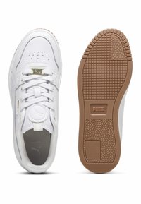 Baskets blanches avec une tige en cuir, bout perforé, accents dorés, semelle extérieure en caoutchouc avec une adhérence texturée, et logo Puma bien visible.