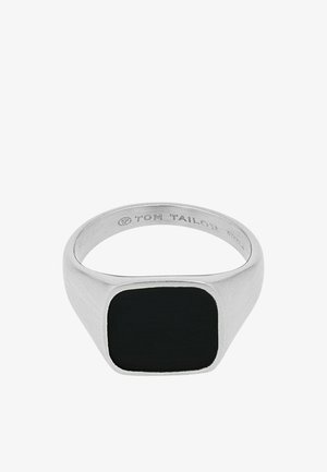 Zilverkleurige metalen ring met een glad, vierkant zwart steentje bovenop en "Tom Tailor" gegraveerd aan de binnenkant van de band.
