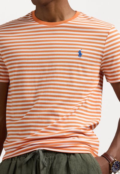 Πορτοκαλί και λευκή ριγέ μπλούζα με στρογγυλή λαιμόκοψη και μπλε κεντητό λογότυπο στο αριστερό στήθος. Μαλακό ύφασμα, άνετη εφαρμογή.