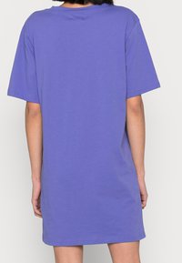 Sukienka z krótkim rękawem w jasnofioletowym kolorze wykonana z bawełny, z luźnym krojem i okrągłym dekoltem, z widocznymi detalami szycia.