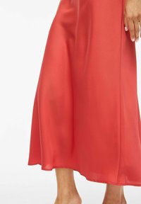 Vestido de satén rojo con una silueta fluida, que presenta una textura suave, forma en A y un dobladillo que cae por debajo de la rodilla.
