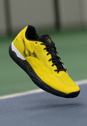 Yellow athletic shoe featuring a textured mesh upper, black accents, and a pronounced rubber sole with a wave-like pattern.