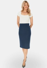 Granatowa spódnica ołówkowa o gładkiej fakturze, z wysokim stanem i bocznym zamkiem błyskawicznym. Zestawiona z dopasowanym białym topem.