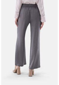 Graue weit geschnittene Hosen mit elastischem Bund, aus leichtem Stoff. Kombination mit beigefarbenen, lackledernen Blockabsatzschuhen.