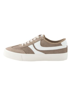 Niskie beżowe zamszowe sneakersy z białymi zygzakowatymi paskami po bokach, białymi sznurowadłami i grubą białą gumową podeszwą.