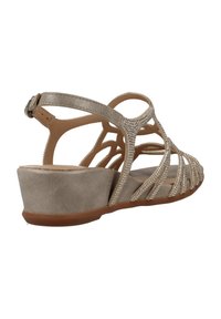 Sandalia de cuña beige con tiras decoradas, diseño abierto, hebilla ajustable en el tobillo y suela texturizada para mayor agarre.