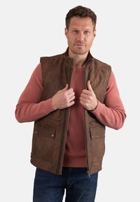 Brown quilted leather vest with two front pockets, zip closure, and a standing collar, layered over a textured pink sweater.