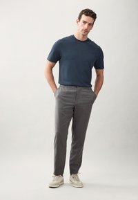 Dark blue short-sleeve t-shirt paired with gray patterned trousers and beige sneakers. Trousers feature a relaxed fit and elastic waistband.