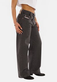 Gray wide-leg jeans made of denim with copper-toned hardware, front pockets, and a branded patch on the waistband. Textured fabric.