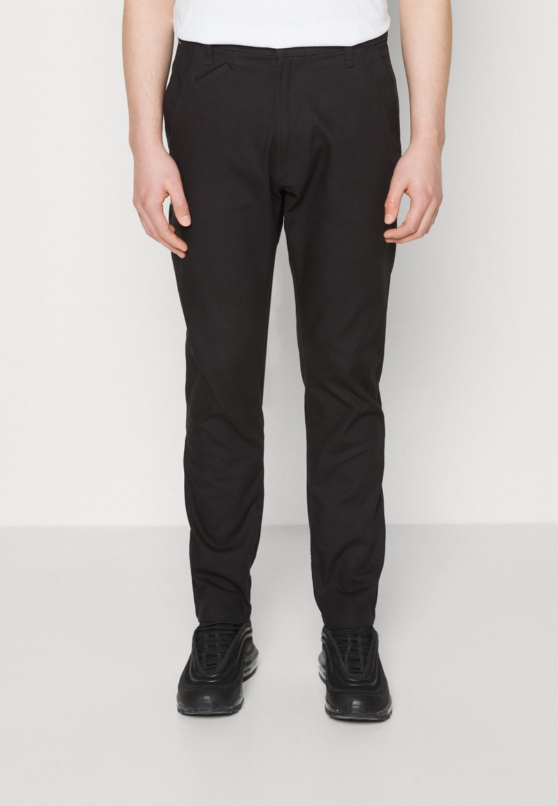 Zwarte broek met een slim fit ontwerp, voorzien van een gladde stoftextuur, zijzakken en subtiele stikseldetails.