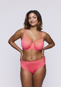Set di lingerie corallo con dettagli in pizzo. Il reggiseno è dotato di ferretto e più bretelle, mentre la parte bassa a vita alta presenta accenti in pizzo.