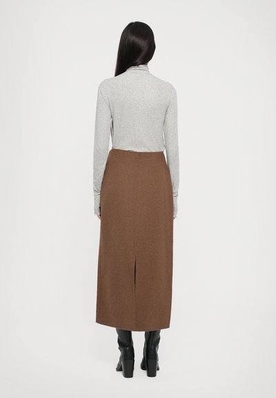 Gray long-sleeve top paired with a brown, knee-length A-line skirt featuring a back slit. The skirt has a soft, textured finish. Black heeled boots.