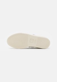 Suola di sneaker bianca con scanalature testurizzate, caratterizzata da un'impronta del logo discreta. Realizzata in gomma naturale, progettata per durabilità e aderenza.
