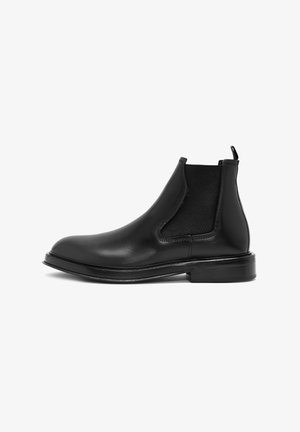 Schwarze Leder-Chelsea-Boots mit elastischen Seiteneinsätzen, runder Spitze und flacher Sohle. Verfügt über eine Zugschlaufe für einfaches Anziehen. Glatte Textur.