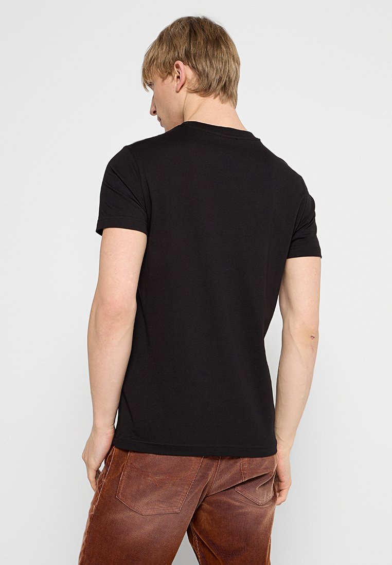 T-shirt noir à manches courtes avec col rond, en coton. Texture lisse, design ajusté, uni sans motifs ni accents.