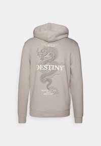Sudadera beige con un gráfico de dragón y texto blanco en la parte posterior. Cuenta con capucha con cordones y puños y dobladillo de canalé. Tela de textura suave.