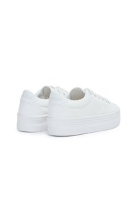 Baskets en toile blanches avec une semelle plateforme épaisse, un bout rond et des coutures ton sur ton. Elles présentent un talon arrière texturé et un design minimaliste.