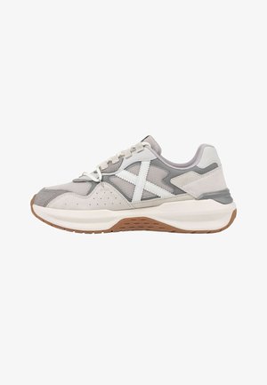 Sneaker grigio chiaro e bianco con pannelli in mesh e suede, lacci bianchi, suola bianca spessa e suola esterna marrone testurizzata, vista laterale.