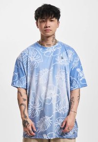Light blue short-sleeved T-shirt featuring white floral patterns, with a relaxed fit and soft texture. Includes a small logo on the chest.