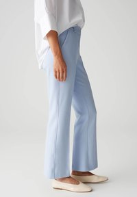 Helleblaue ausgestellte Hosen aus glattem Stoff, mit einer mittelhohen Taille, seitlichen Eingrifftaschen und einem sauberen Schnitt am Saum.