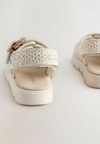 Weiße geflochtene Sandalen mit einem strukturierten Riemen und einer leichten, gepolsterten Sohle. Verfügt über verstellbare Beschläge und eine glatte Innensohle.