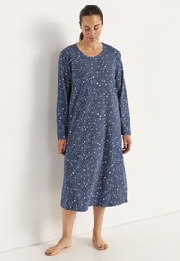 Mörkblå bomullsnattklänning med långa ärmar och rundad halsringning, med ett vitt stjärnmönster och en avslappnad passform som når till mitten av vaden.
