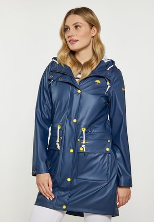 Chubasquero impermeable de color navy con capucha, herrajes dorados, cordones, bolsillos frontales y un logo de paraguas amarillo en el pecho. Textura suave.