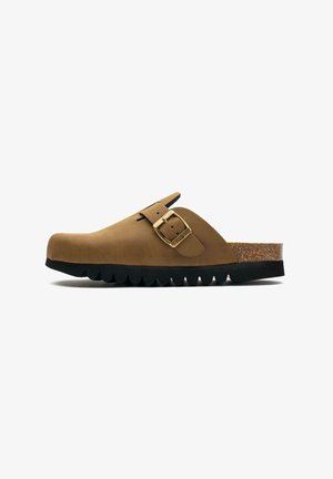 Brown suede clog with a curved shape, buckle detail, cork footbed, and a thick black rubber sole featuring scalloped edges.